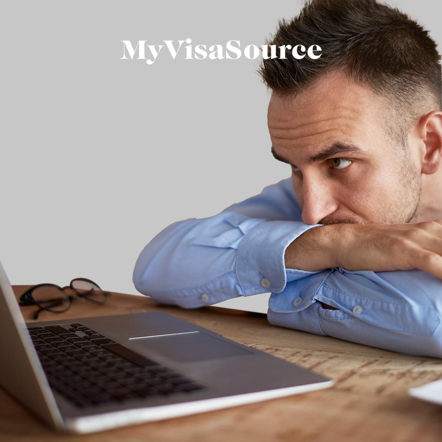 man with crossed arms looking frustrated in front of laptop my visa source
