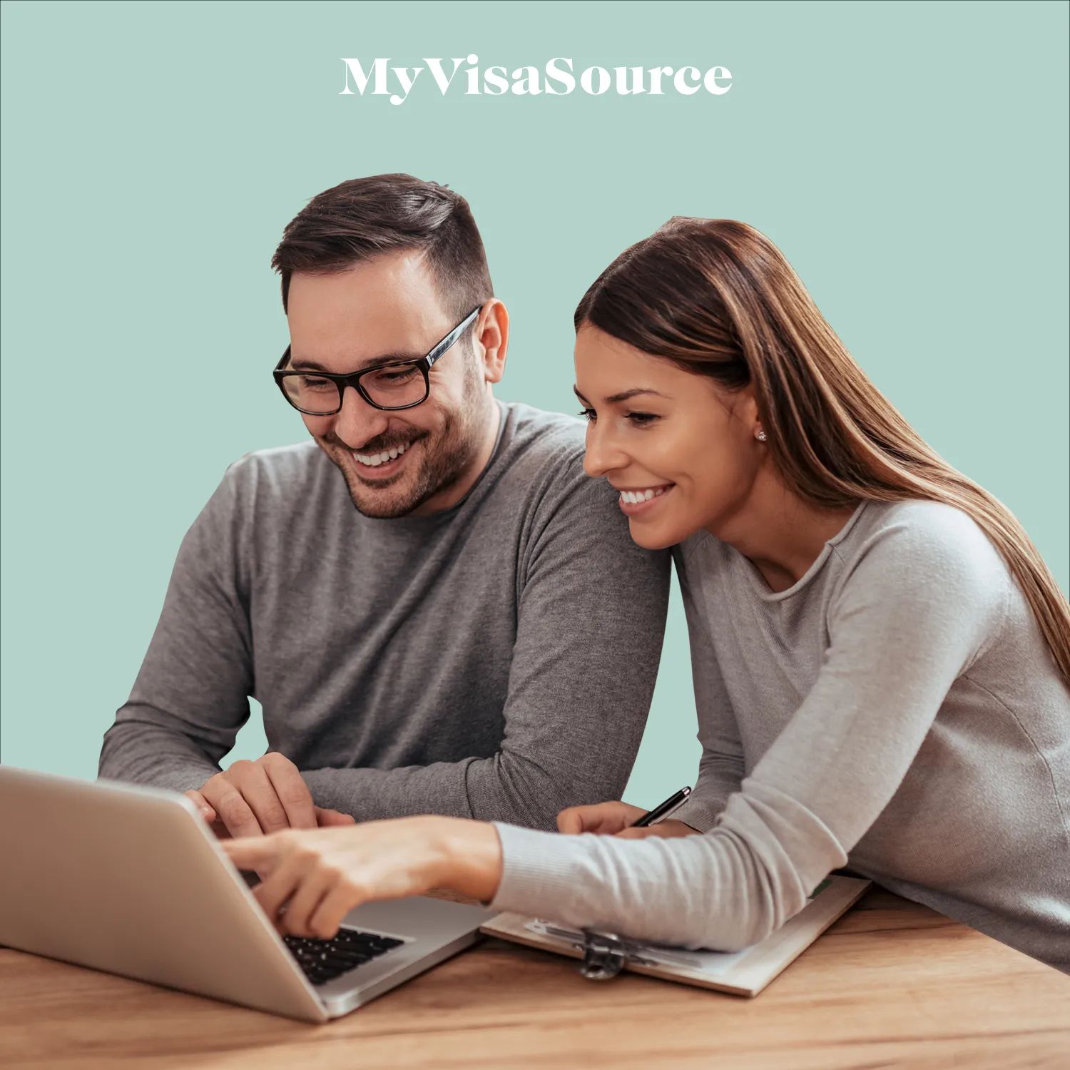 happy couple working on laptop and taking notes with turquoise background by my visa source