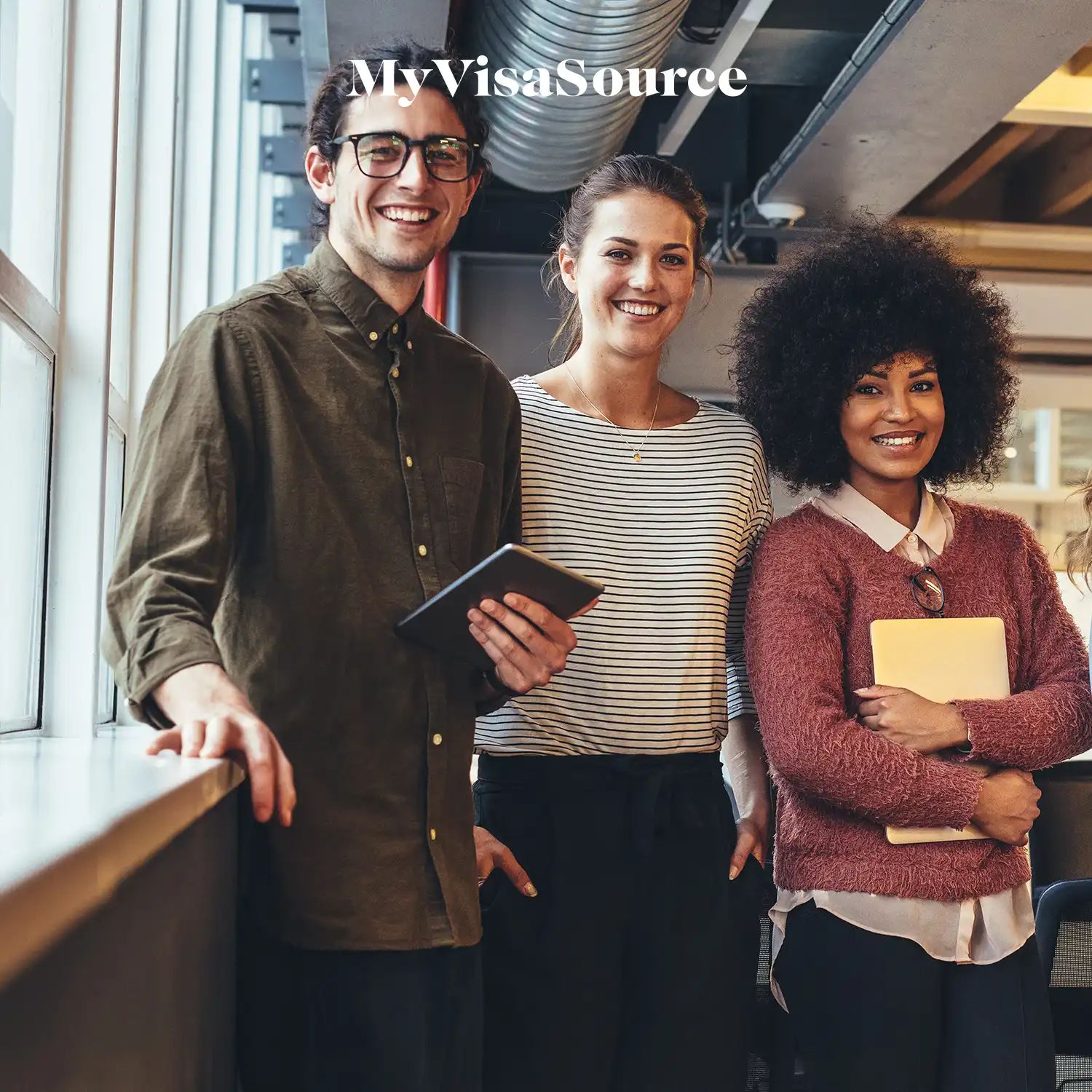 three cheerful co workers with tablets in hand at a casual workspace by my visa source