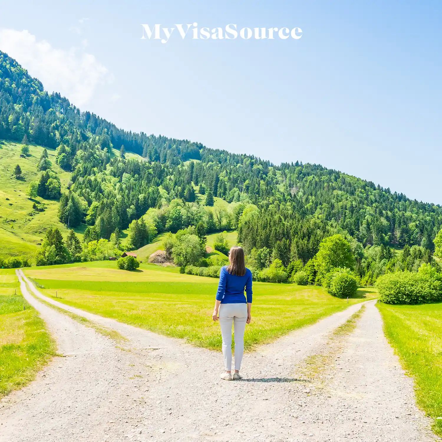 woman standing at a fork in the road with two different paths going into the hills and woods by my visa source