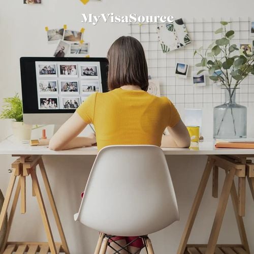 a woman working at her desk by my visa source