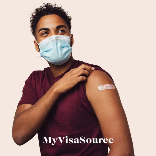 man with a mask on and vaccination bandage on arm